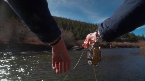 POV-Hände-Mit-Fliegenfischerrute,-Die-Goldene-Leine-Am-Forellenfluss-Einholen