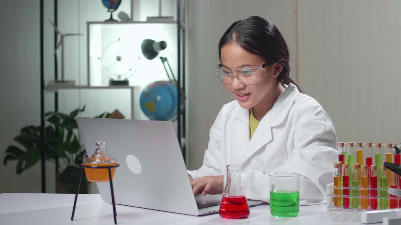 Young Asian Scientist Girl Using Lap Top Computer In Laboratory Experiment With Liquid