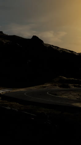 winding road through dark mountains at sunset