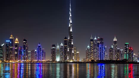 colorful lights illuminating dubai skyscrapers and reflecting on water surface at night, with burj khalifa standing out amongst other buildings