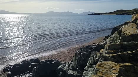 hazy snowdonia mountain range across idyllic slow motion shimmering irish seascape dolly left from rocks