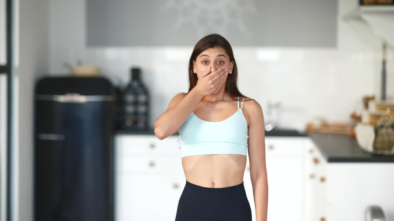Woman in sportswear surprised in the kitchen