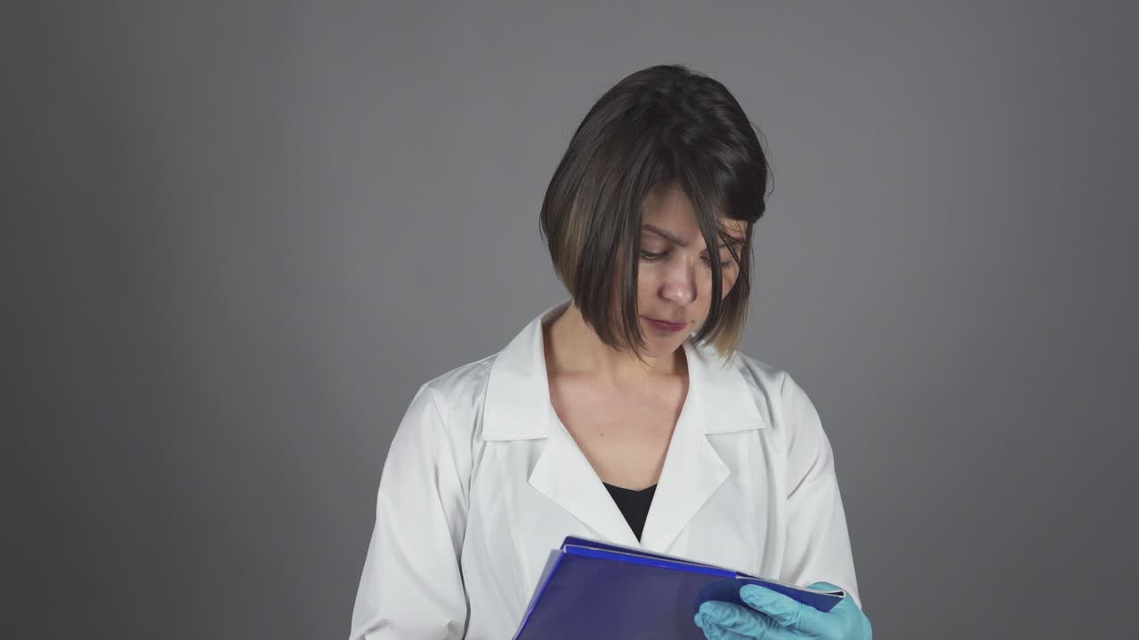 Medical nurse in gloves writing on clipboard isolated on grey background. Healthcare concept. Shot in 4K.