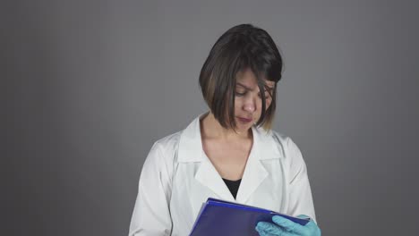 enfermera médica con guantes escribiendo en un clipboard aislado en un fondo gris. concepto de atención médica. filmado en 4k.