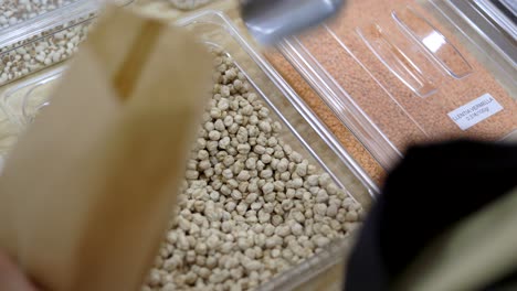 un tendero llenando un frasco de vidrio con garbanzos