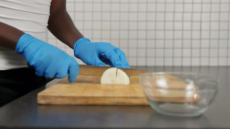 african lady cutting onion with gloves - food prep during covid