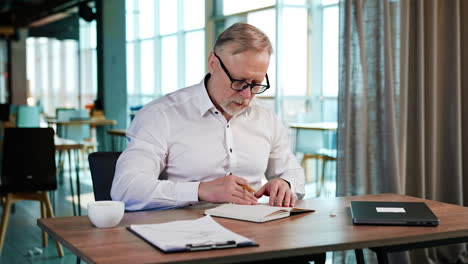 bearded caucasian man opens his paper notebook. man turns the pages of his book, grimaces and gestures.