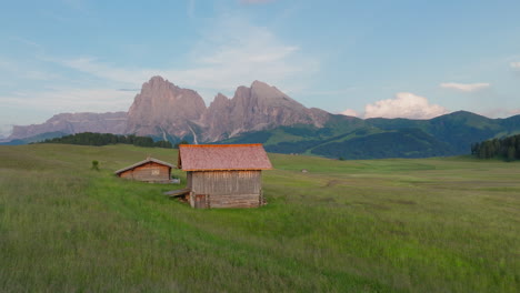 single hut on alpe di siusi field with dolomite mountains behind during golden sunset
