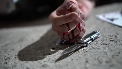 mano sangrienta con cuchillo y carta de suicidio en el suelo, vista del suelo de cerca