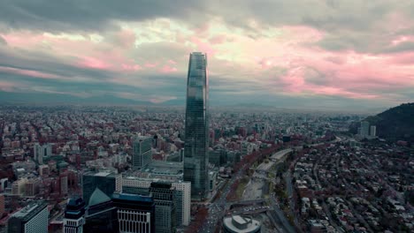 aerial orbit of the financial center with the costanera tower, cloudy sunset after rain in the background, mapocho river with bridges, providencia district, santiago, chile