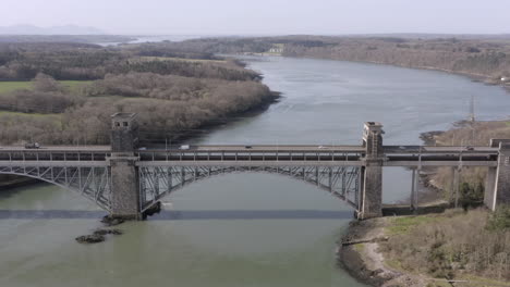 aerial view of the pont britannia railroad bridge, flying left to right around the bridge on a sunny day, anglesey, north wales, uk