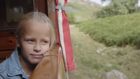 girl looking out a window of a wooden cabin