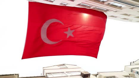 really big turkish flag in slow motion and sunlight leaks between buildings, turkey country