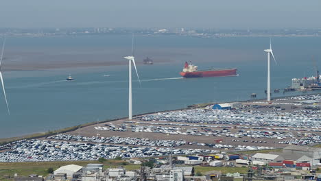 Telephoto-aerial-view-tracking-a-container-ship-passing-by-Sheerness-Port,-on-the-Isle-Of-Sheppey,-Kent,-UK