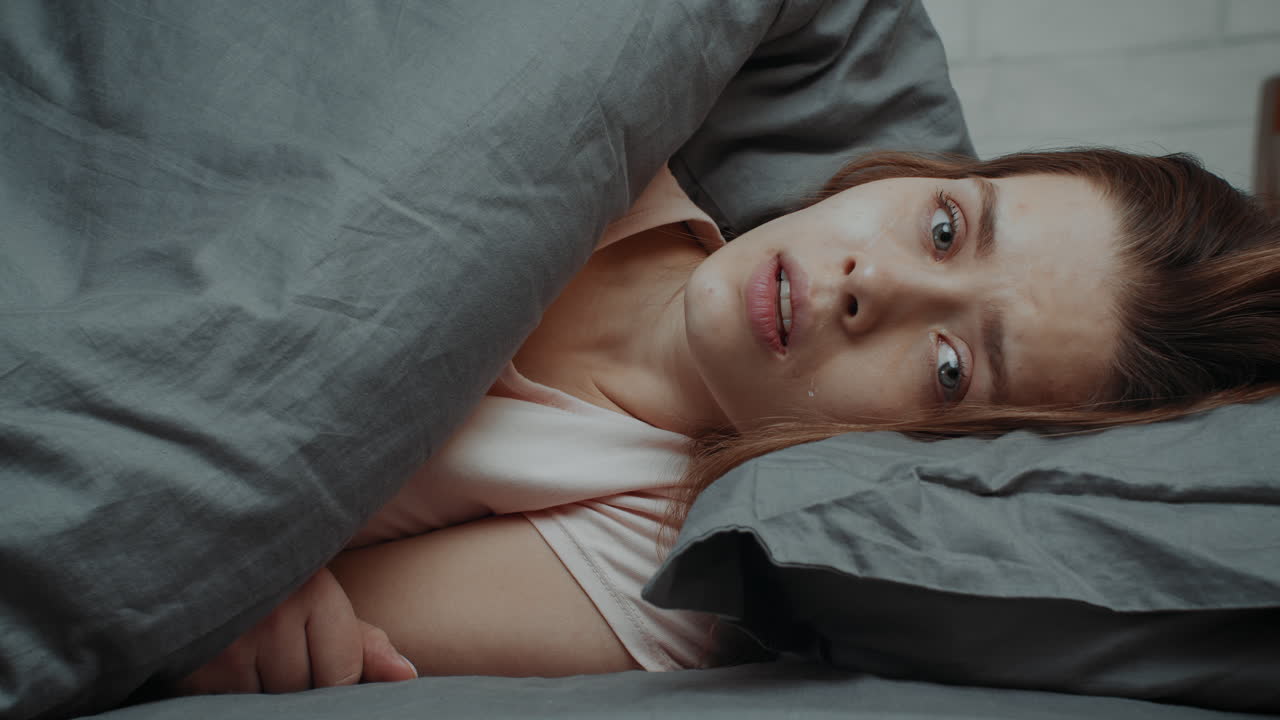 una mujer llorando en la cama.