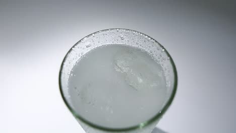 topview,-pouring-sparkling-water-into-glass,-ice-cubes,-serving-beverage-drink