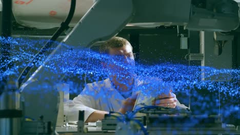 Animation-of-blue-glowing-mesh-over-male-scientist-with-robot-and-tablet