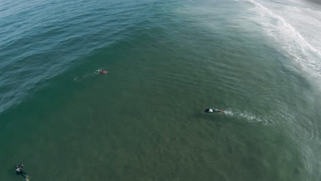 Gentle-sweeping-overview-of-ocean-waves-and-bodyboarders-swimming-out-to-lineup