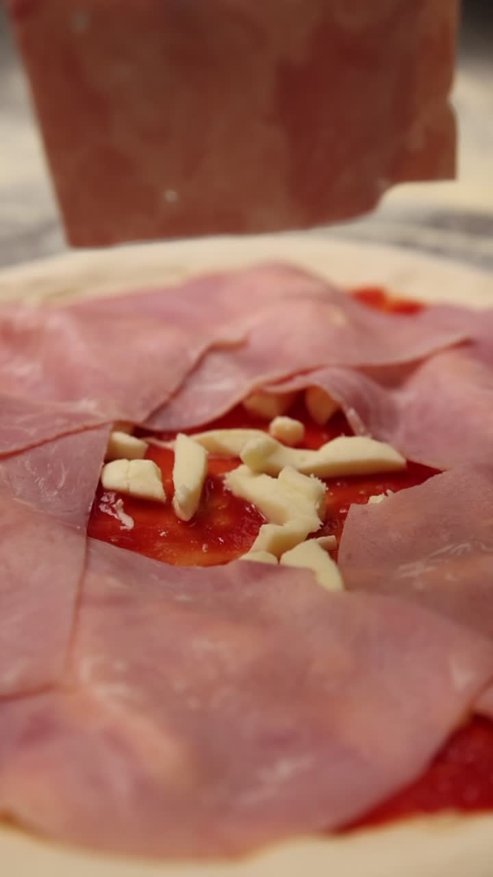 Mano che posiziona fette di prosciutto sull'impasto della pizza