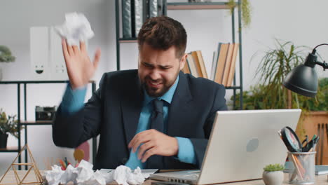 angry furious man working at home office throwing crumpled paper having nervous breakdown at work
