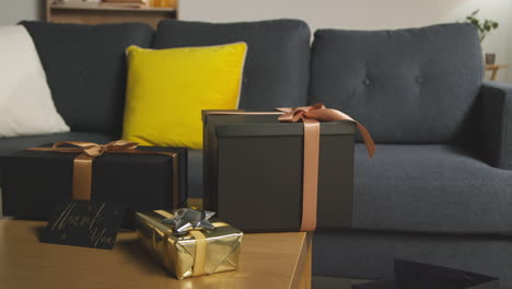 close up of man putting thank you card next to gift wrapped presents on table in lounge at home