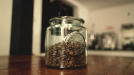 freshly roasted coffee beans falling into a glass container, side bottom view to top