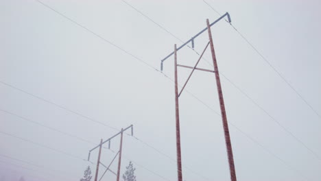 a wide shot of tall power lines as it snows