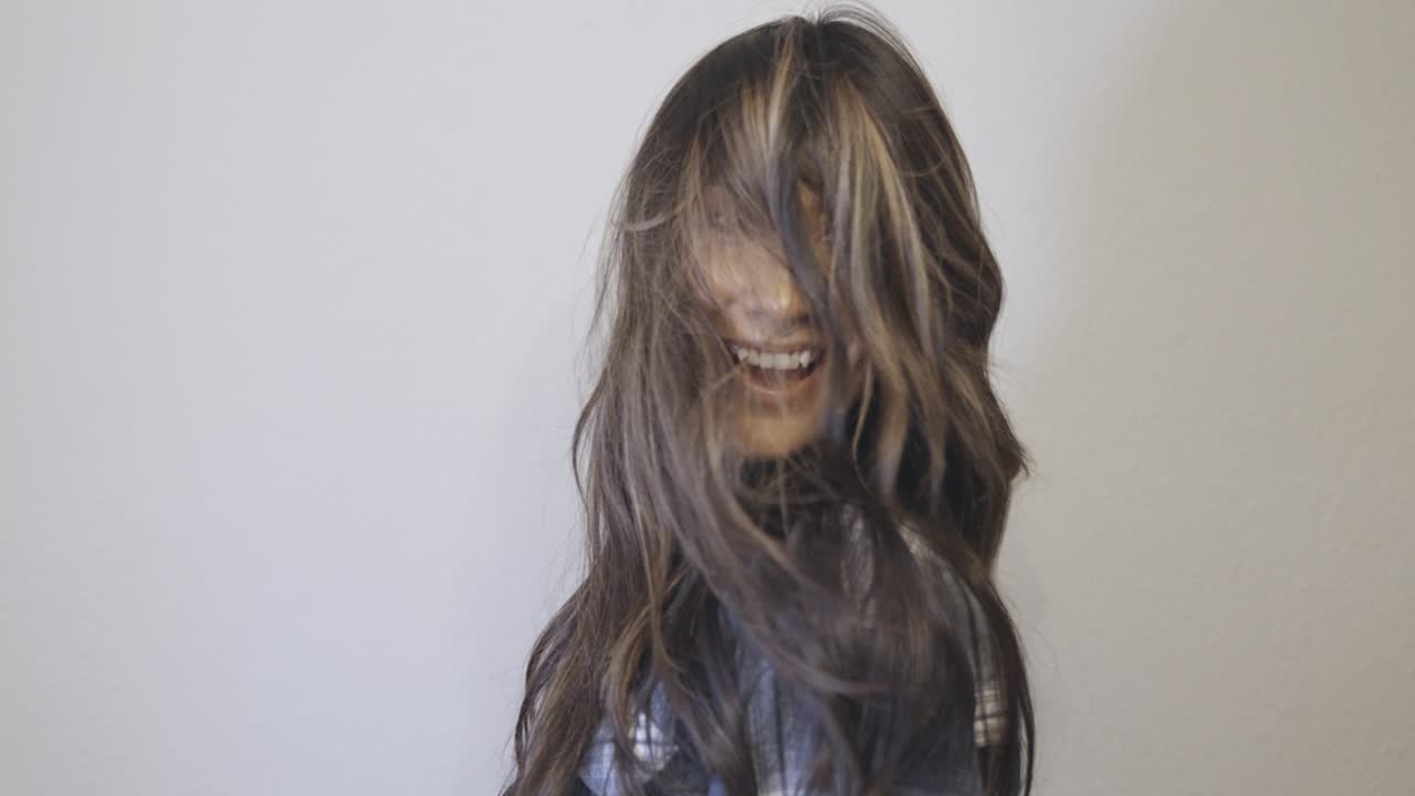 una mujer hispana voltea su cabello dos veces y sonríe