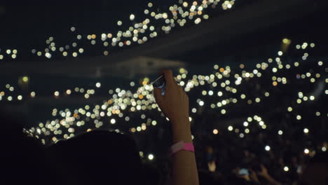 audience with lights in concert hall and woman taking mobile video