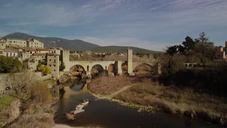 mittelalterliche brücke und fluss in der stadt besalu, girona, spanien, umgeben von historischen gebäuden und natur