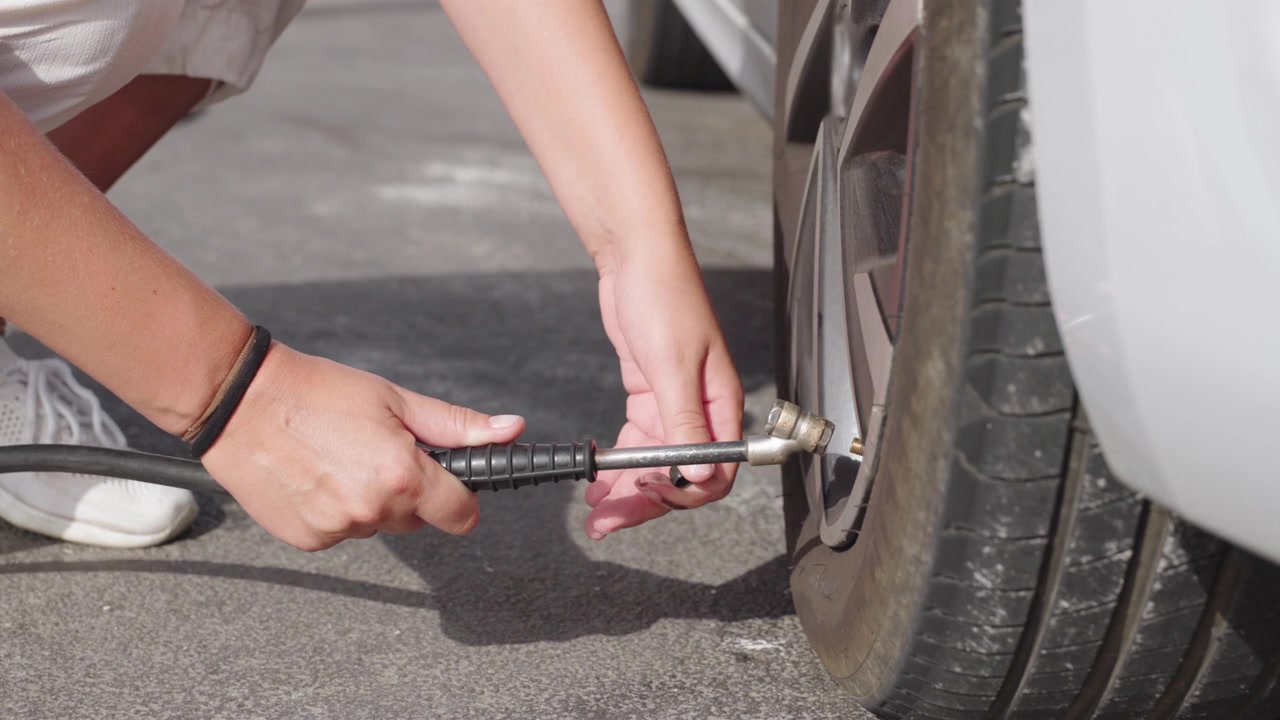 Person inflating a vehicle tire with an air hose