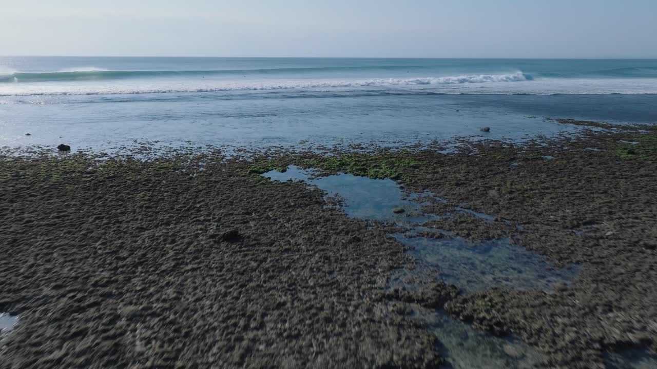 tomada de drone de ángulo bajo del arrecife de marea baja y las olas en uluwatu bali, indonesia