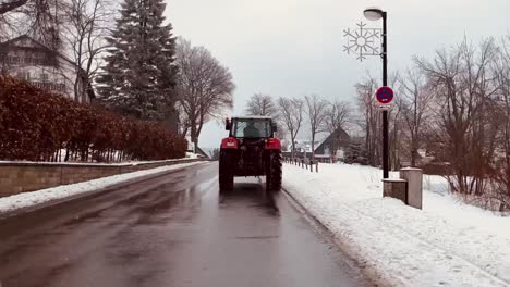 Tractor-drives-through-winter-village-with-light-snow-past-small-houses