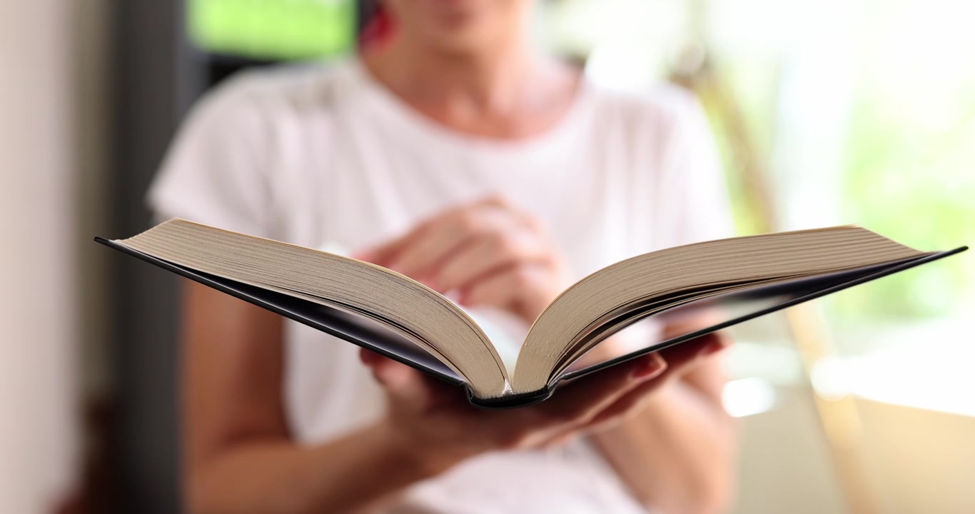 A woman leaf through the pages of a large book