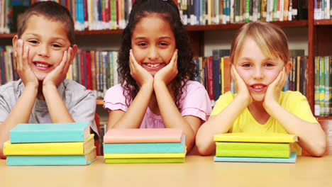 alumnos sonriendo a la cámara en la biblioteca