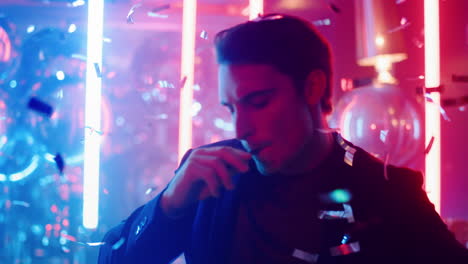 Sexy-man-dancing-under-confetti-in-club.-Guy-smoking-on-neon-lamps-background