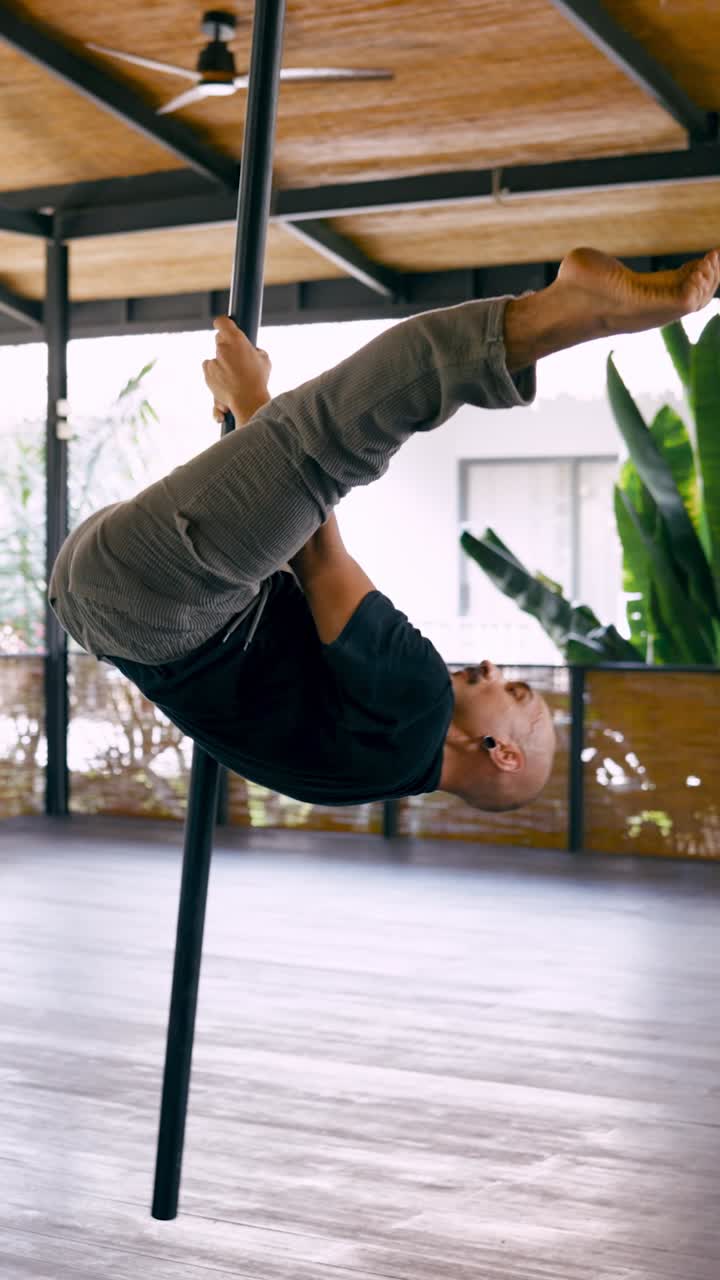 Athletic Man Performing Acrobatic Pole Dance Moves