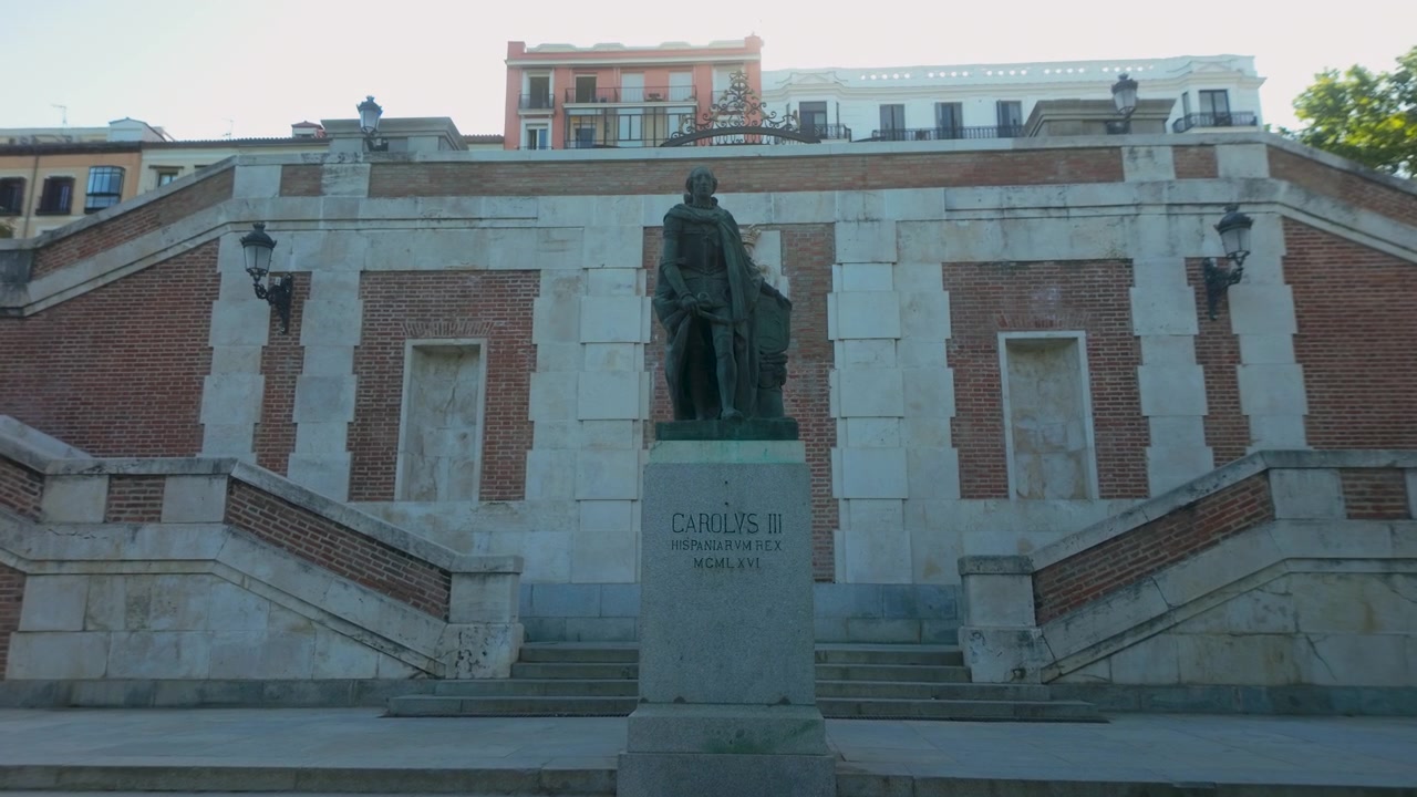 Una toma en contrapicado de la estatua de bronce de Carlos III de pie frente a grandes escaleras de piedra en Madrid. Ideal para documentales de viajes y contenido histórico