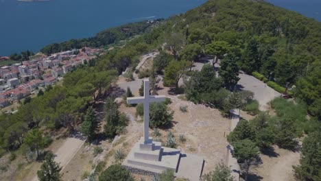 volando sobre una cruz blanca de suma marjan en croacia, con la cruz como tema principal y el mar adriático azul como fondo
