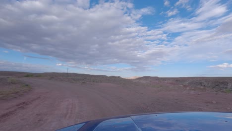 conducir por un camino de tierra en un paisaje desértico árido - punto de vista del conductor durante el día