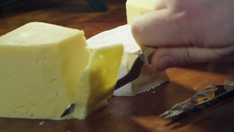 three cheeses on wooden board, gouda cheese sliced with knife, taken