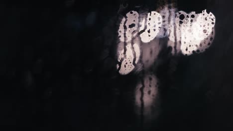 gotas de lluvia en un panel de vidrio con luces de coche en el fondo