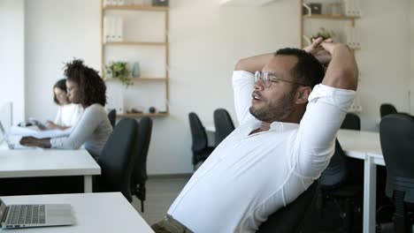 Side-view-of-focused-young-man-typing-on-laptop-and-rejoicing