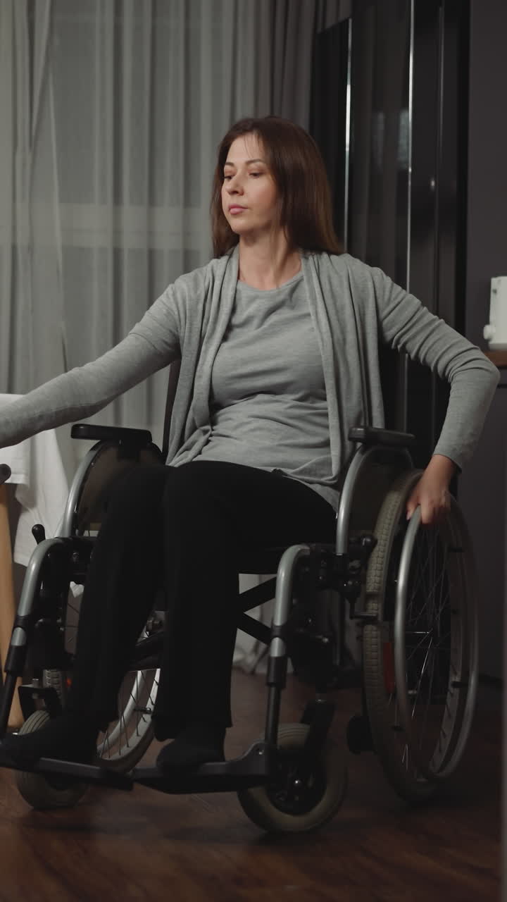 mujer se mueve en una habitación acogedora girando grandes ruedas de silla de ruedas y sosteniendo una aspiradora inalámbrica. joven ama de casa aspira el suelo manteniendo limpio el apartamento