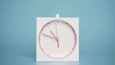 white alarm clock isolated on a blue background, time starts walking at 10 o'clock.