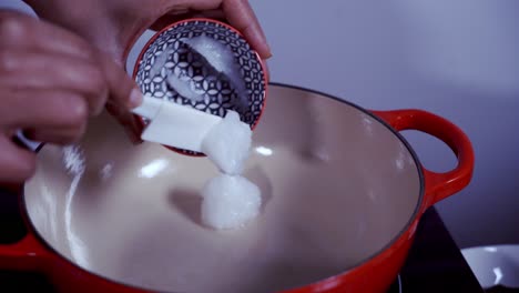 añadir aceite de coco solidificado en una olla de hierro fundido para hacer curry de papaya verde