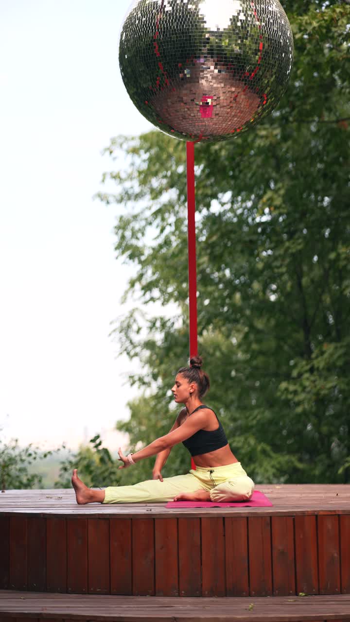 mujer haciendo yoga al aire libre con una pelota de discoteca