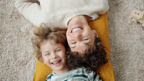 happy mother and son laying on carpet