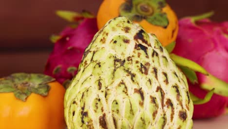 arrangement of dragon fruit, persimmon, and cherimoya