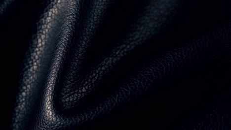 close-up shot of black leather with slowly shifting folds and wrinkles, captured under cinematic lighting. the smooth, matte texture and subtle motion create a sophisticated and tactile visual.